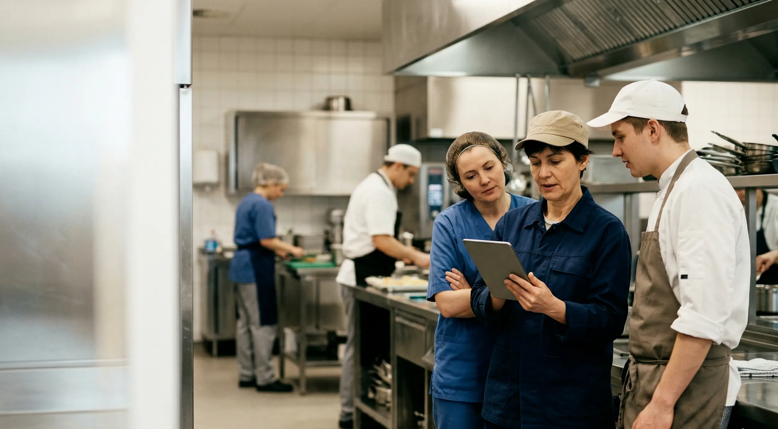 Kitchen staff using digital checklist on tablet during food preparation